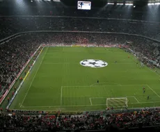 Un stade de football avec une grande écran d'affichage et un logo au centre du terrain de jeu.