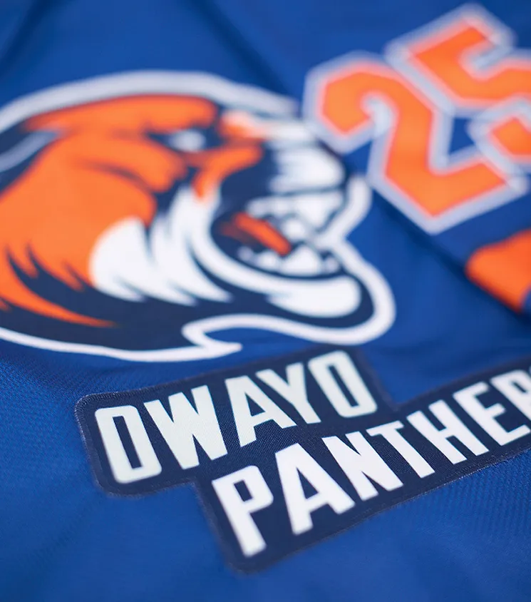 Plan rapproché d'un maillot de sport bleu avec un logo de panthère orange et l'inscription 'OWAYO PANTHERS' en lettres blanches sur un patch sombre.
