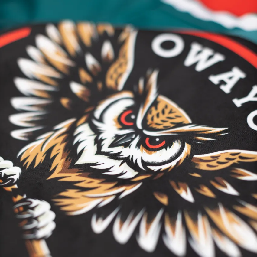 Un design coloré et détaillé d'un motif de hibou sur fond noir, présenté sur un vêtement de sport d'owayo.