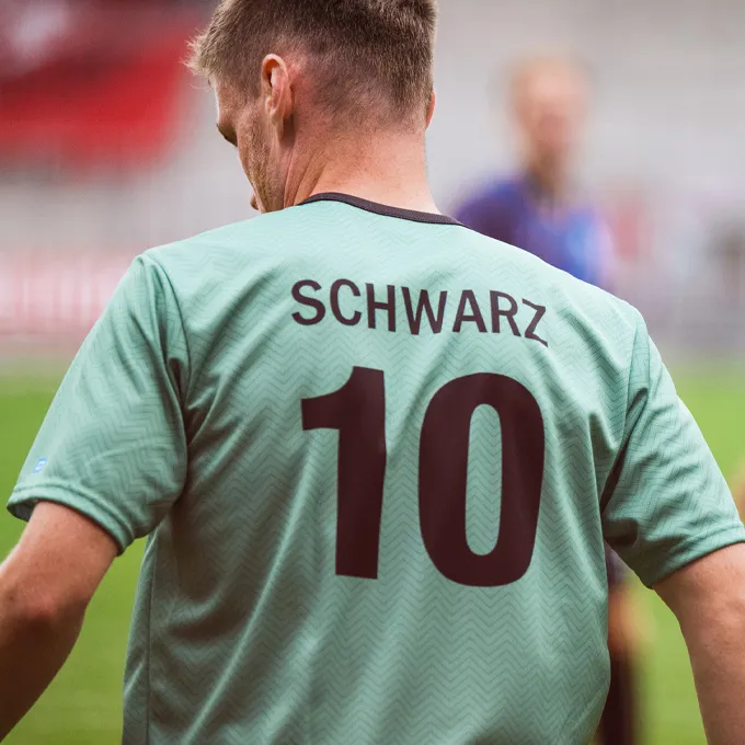 Un joueur porte un maillot de football vert menthe avec le numéro 10 et le nom 'SCHWARZ' dans le dos.