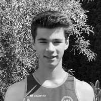 Un jeune homme portant un maillot de sport sans manches noir et gris avec le logo 'owayo' sur la poitrine, sourit devant un fond de feuilles vertes.