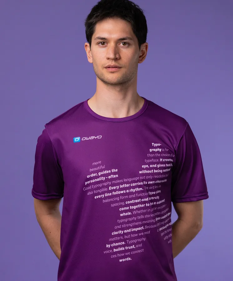 Un homme porte un t-shirt de sport violet avec un texte typographique sur le devant, sur un fond violet.