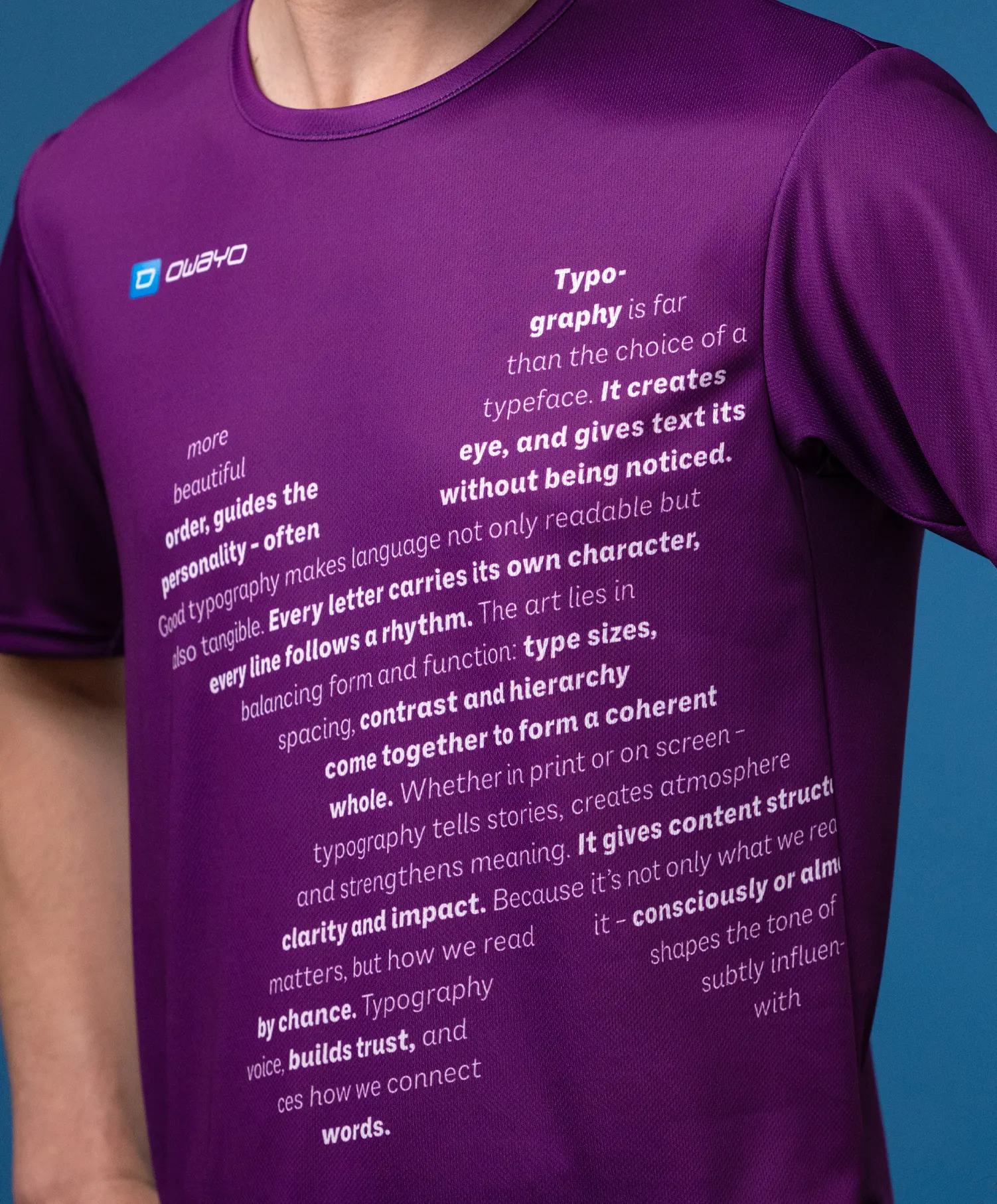 Un gros plan sur un t-shirt de sport violet avec différents textes typographiques sur le devant, porté par un modèle.