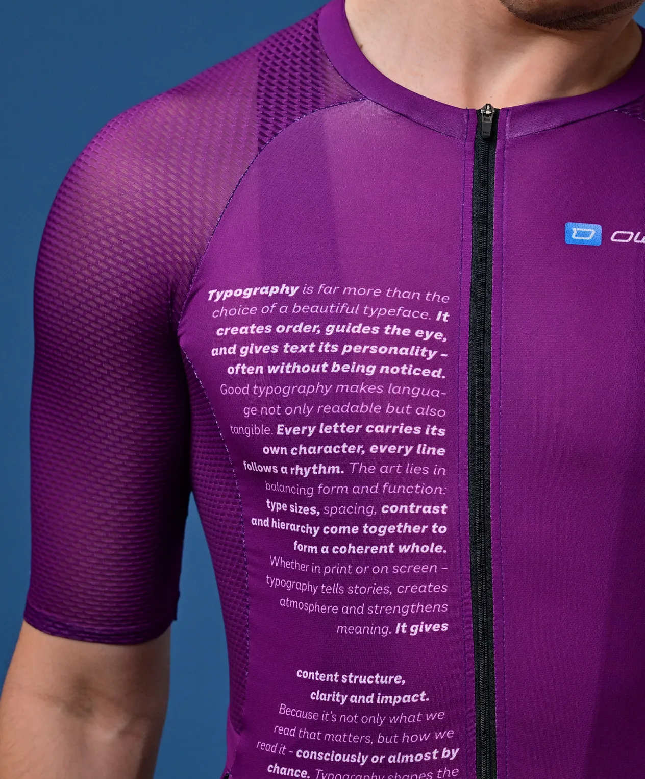 Un homme porte un maillot de sport violet à manches courtes avec un texte sur la typographie sur la poitrine et un petit logo sur l'épaule.
