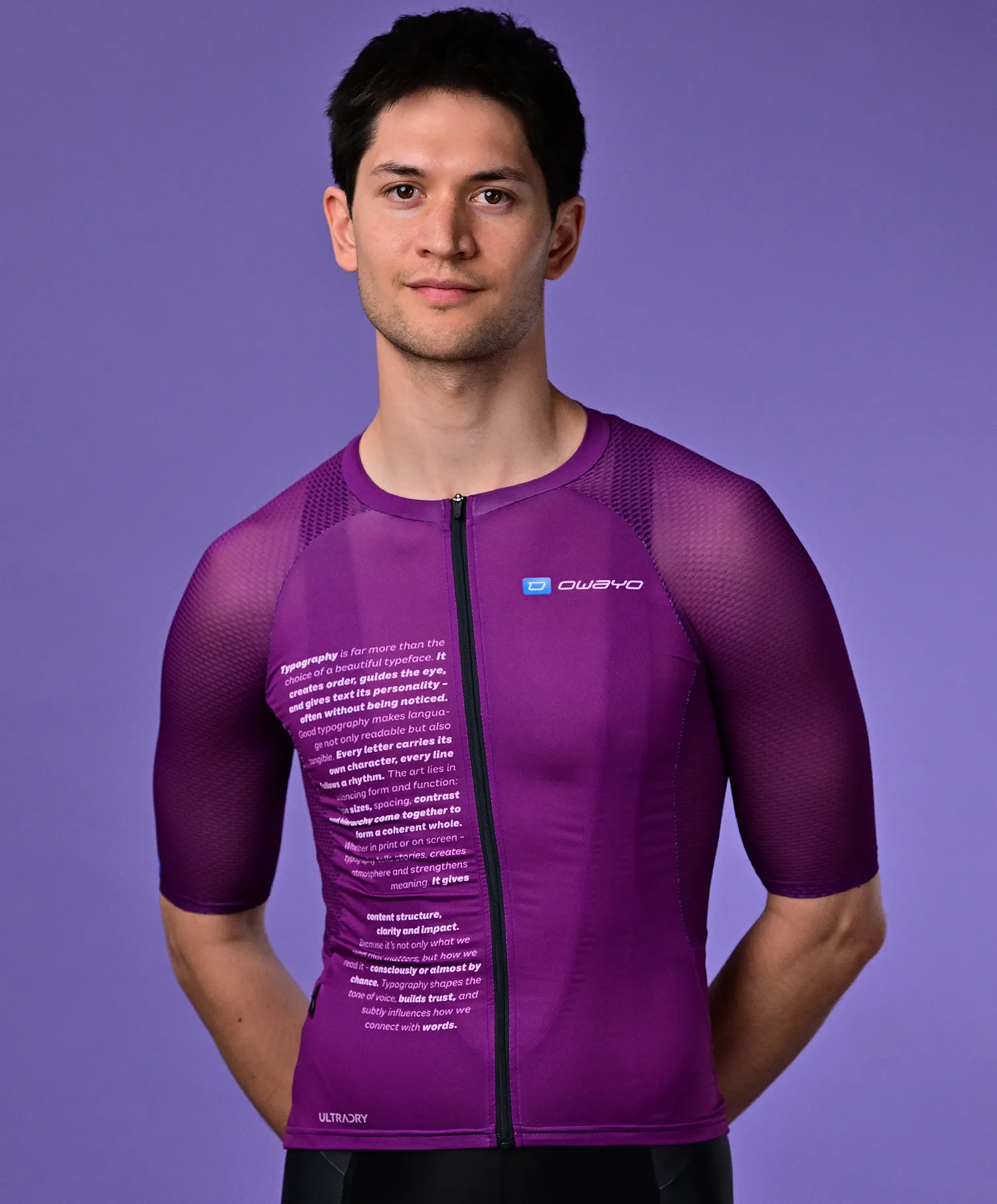 Un homme portant un maillot de sport violet à manches courtes d'owayo avec du texte sur la poitrine et le logo owayo sur la poitrine droite.