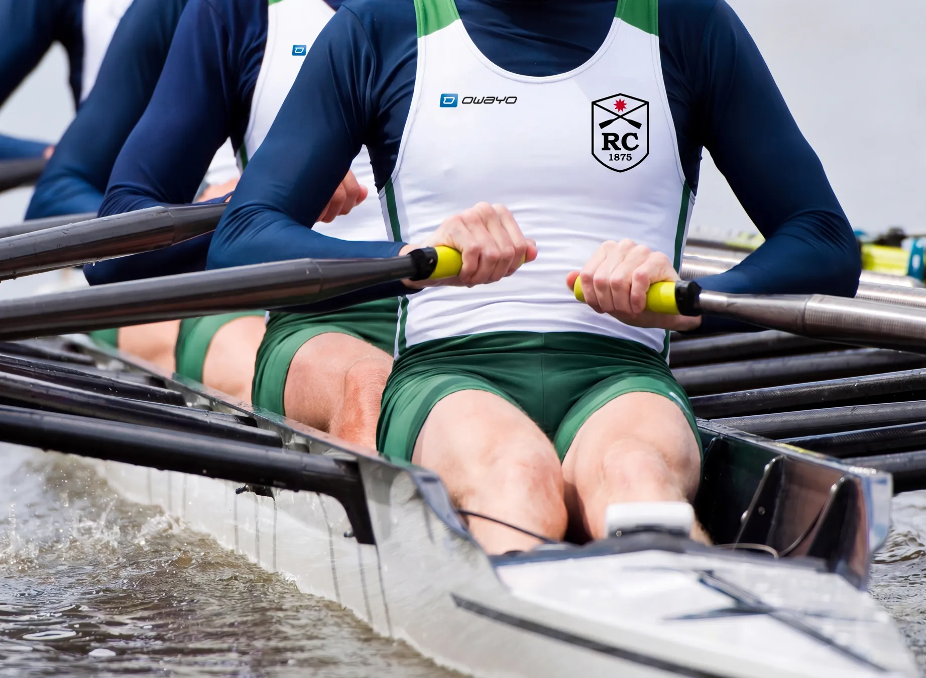 Trois rameurs en vêtements de sport personnalisés rament de manière synchronisée dans un bateau.