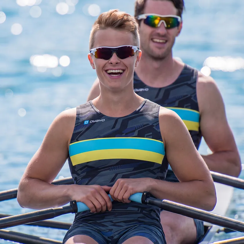 Deux rameurs dans un bateau portent des vêtements de sport personnalisés au design moderne et aux couleurs vives.
