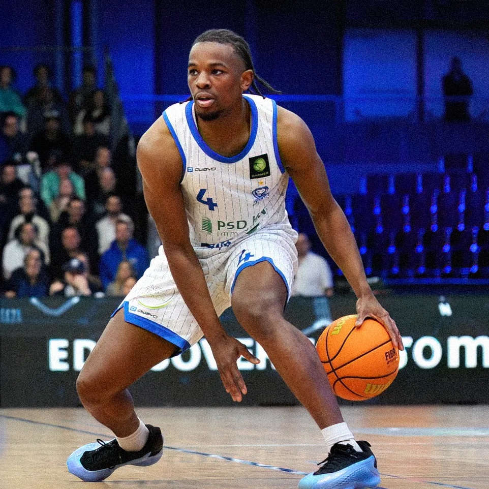 Un joueur de basket-ball dribble le ballon sur le terrain tout en portant un maillot rayé avec le numéro 4.