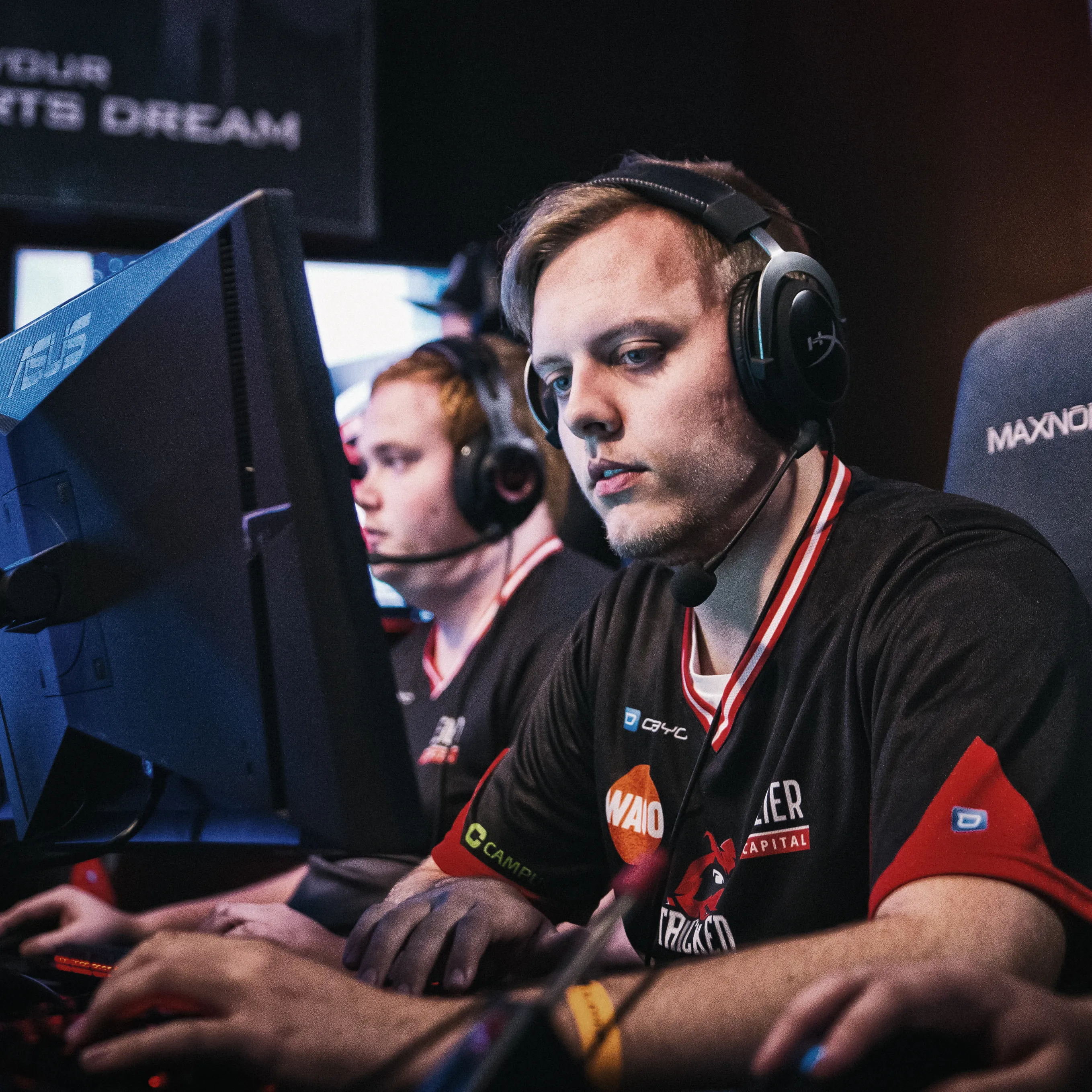 Deux joueurs en t-shirts de sport avec des casques, concentrés sur leurs ordinateurs lors d'un tournoi d'eSports.